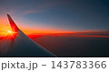 Airplane wing silhouette against blazing golden orange sunset and clouds 143783366