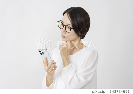 スマホを持って考えるミドル女性 白背景 スマホを持って考えるミドル女性 白背景 143784691