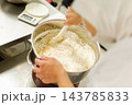 ボウルでの生地混ぜ作業　ゴムベラで粉と材料を混ぜ合わせる様子　洋菓子製造　製菓工程 143785833