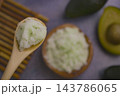 A spoon holds avocado scrub in closeup . 143786065