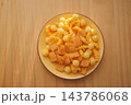 Bowl of cheese crackers and puffed snacks on a wooden table 143786068