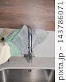 Hands remove a mesh sink strainer from a kitchen faucet 143786071