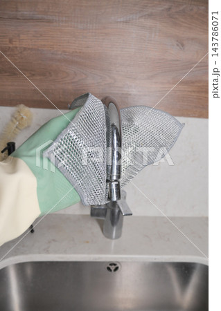 Hands remove a mesh sink strainer from a kitchen faucet 143786071