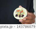 Hand holding a round white dessert topped with almonds and pistachios 143786079