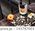 Ceramic Essential Oil Burner with Candle Flame, Pebbles, and Plumeria Flowers in Spa Setting 143787003