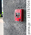 Red Fire Alarm Pull Station Mounted on Textured Concrete Stone Wall 143787004