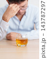 Stressed man drinking whiskey alone with problem. Exhausted drunk man looking stressed and sleepy. Alcohol addiction, Alcoholism, emotional distress and mental health concept 143787297