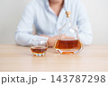 man with glass of cognac on table, suffering from alcohol addiction and alcoholism concept. depicting emotional distress, depression, substance abuse problem, unhealthy lifestyle and mental health 143787298