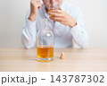 Stressed man drinking whiskey alone with problem. Exhausted drunk man looking stressed and sleepy. Alcohol addiction, Alcoholism, emotional distress and mental health concept 143787302