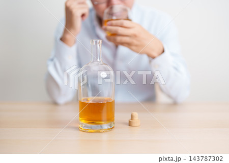 Stressed man drinking whiskey alone with problem. Exhausted drunk man looking stressed and sleepy. Alcohol addiction, Alcoholism, emotional distress and mental health concept Stressed man drinking whiskey alone with problem. Exhausted drunk man looking stressed and sleepy. Alcohol addiction, Alcoholism, emotional distress and mental health concept 143787302