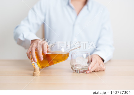 man pour whiskey into a glass on table, suffering from alcohol addiction, alcoholism concept. depicting emotional distress, depression, substance abuse problem, unhealthy lifestyle and mental health 143787304