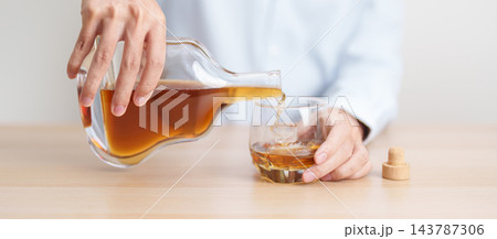 man pour cognac into a glass on table, suffering from alcohol addiction, alcoholism concept. depicting emotional distress, depression, substance abuse problem, unhealthy lifestyle and mental health 143787306