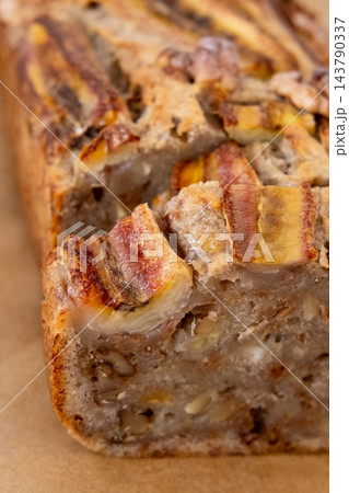 Homemade cake. Sweet loaf. Baked aromatic banana bread garnished with caramelized fruit walnut served by slices on parchment paper. 143790337