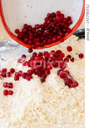 Berry pastry preparation. Baking cookies. Pouring red cranberry from bowl in flour crumbs pile making sweet treat with natural flavor. 143790352
