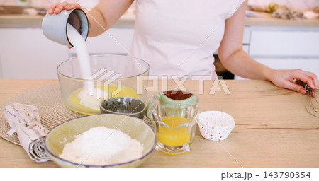 Home recipe. Dessert preparation. Baker female adding measured sugar egg to bowl with batter on table with baking ingredient dish. Home recipe. Dessert preparation. Baker female adding measured sugar egg to bowl with batter on table with baking ingredient dish. 143790354
