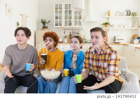Group of friends watching sport match soccer football game on tv. Happy football fans celebrating victory at home. Friendship sports entertainment concept. Diverse buddies having fun together at home 143790452