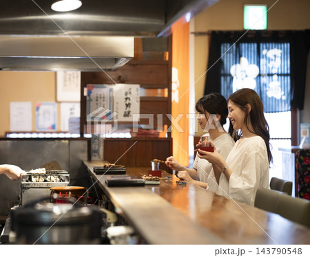 カウンター席で焼き鳥と日本酒を楽しむ2人の若い女性 カウンター席で焼き鳥と日本酒を楽しむ2人の若い女性 143790548