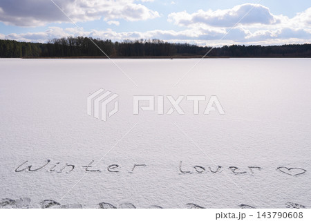Written WINTER LOVER on snow background message ice outdoor on ground in winter. Writing text sign and drawing on field in frozen background. Weather is changing cold season has arrived. Mockup Copy Written WINTER LOVER on snow background message ice outdoor on ground in winter. Writing text sign and drawing on field in frozen background. Weather is changing cold season has arrived. Mockup Copy 143790608