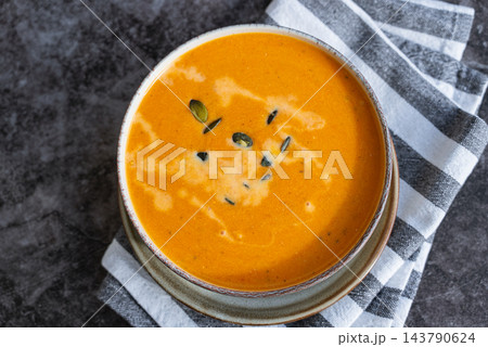 Smooth texture natural colors and fresh dairy contrast beautifully with the garnish of Creamy Pumpkin Soup Garnished with Pumpkin Seeds. Concept of homemade cooking seasonal ingredients 143790624