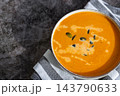 Bowl of creamy pumpkin soup topped with pumpkin seeds. Rich orange puree is served in rustic bowl and decorated with crunchy seeds creating an appetizing autumn meal presentation. Concept of seasonal 143790633