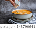 Smooth texture natural colors and fresh dairy contrast beautifully with the garnish of Creamy Pumpkin Soup Garnished with Pumpkin Seeds Cream Pouring by Hand. Concept of homemade cooking seasonal 143790641