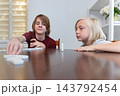Two young boys are sitting at a wooden table, engaging in a game of dominoes, focusing on placing pieces and developing their playing strategy during leisure time 143792454
