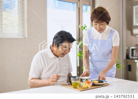 介護施設で食事を提供されるシニア男性とスタッフのシニアの女性 介護施設で食事を提供されるシニア男性とスタッフのシニアの女性 143792531