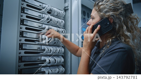 Female IT Specialist Consulting Colleague by Smartphone While Inspecting Server Cable Connections 143792781