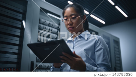 Female Technology Specialist Analyzing Server Room Data on Tablet During IT Assessment Female Technology Specialist Analyzing Server Room Data on Tablet During IT Assessment 143793050