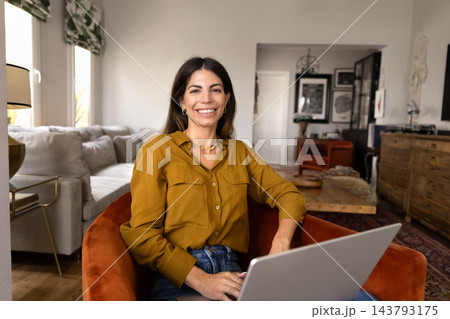 Portrait Hispanic woman working on laptop in cozy home interior 143793175