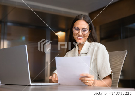 Businesswoman reviewing business documents at office desk Businesswoman reviewing business documents at office desk 143793220