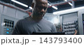 Male IT Specialist Standing in Modern Server Room with Digital Tablet 143793400