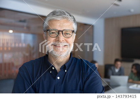 Headshot senior Latino executive smiling at camera during corporate meeting Headshot senior Latino executive smiling at camera during corporate meeting 143793415