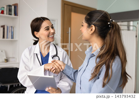 Doctor holding digital tablet and shaking hands with patient 143793432