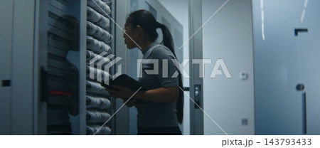 Network Engineer Examining Structured Patch Cables and Reviewing Technical Data on Tablet 143793433