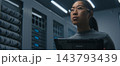 Young Female IT Specialist Reviews Technical Data on Tablet in Modern Server Room. 143793439