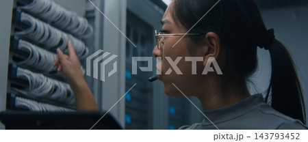 Female Network Engineer Using Tablet and Headset to Coordinate Technical Tasks Female Network Engineer Using Tablet and Headset to Coordinate Technical Tasks 143793452
