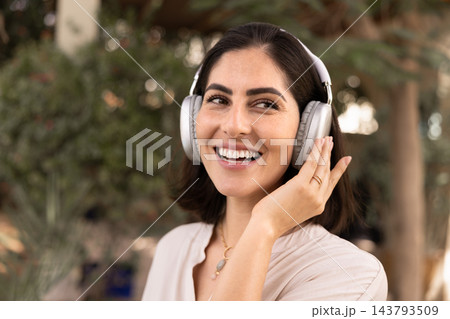 Happy woman listening to music with headphones outdoors Happy woman listening to music with headphones outdoors 143793509