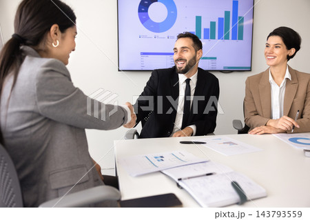 Multiethnic businesswoman and businessman shaking hands in office 143793559