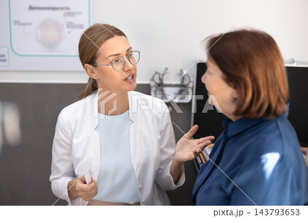 Optometrist discussing eyesight assessment results with senior patient 143793653