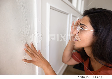 Worried young woman homeowner notice wall imperfection after house improvement Worried young woman homeowner notice wall imperfection after house improvement 143793656