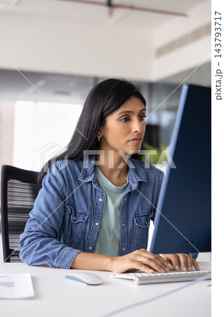 Busy Indian female entering data on computer at office desk 143793717