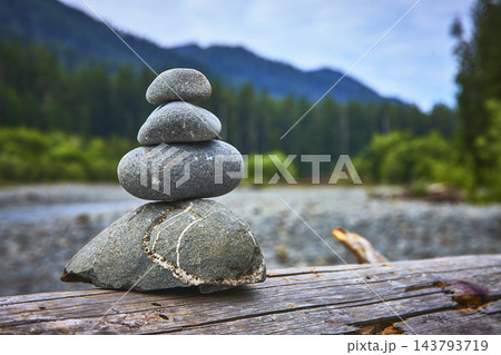 Rock Stack Cairn on Log with Forest and Mountains in Soft Focus Rock Stack Cairn on Log with Forest and Mountains in Soft Focus 143793719