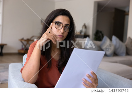 Pensive young businesswoman thinking on documents sitting in comfy armchair Pensive young businesswoman thinking on documents sitting in comfy armchair 143793743