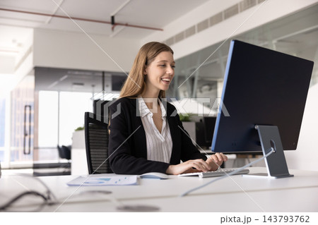 Motivated young female professional working on computer at office desk Motivated young female professional working on computer at office desk 143793762