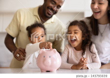 Interracial couple teaching their two little children to save money Interracial couple teaching their two little children to save money 143793839