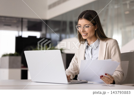 Positive successful financial professional woman in glasses analyzing paper report Positive successful financial professional woman in glasses analyzing paper report 143793883