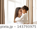Mother holding biracial child in arms at home 143793975