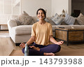 Happy young woman meditating on mat keeping water bottle near 143793988
