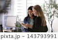 Multiethnic women business professionals checking tablet at modern office workspace 143793991
